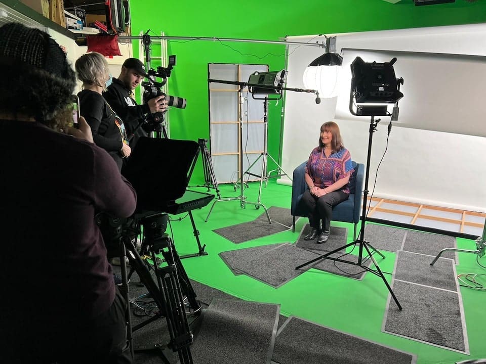 Woman sitting for an interview in studio with white colorama
