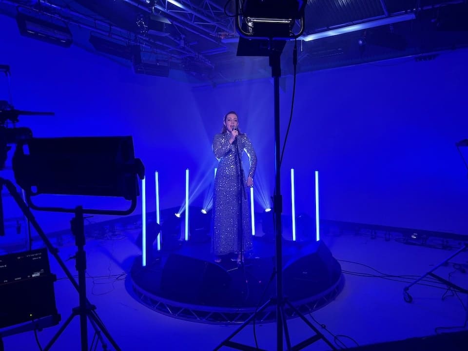 Singer performing in infinity cove studio with blue lighting