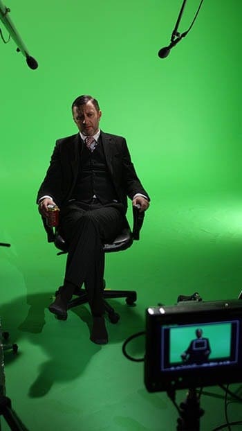 Man sitting on chair in green screen studio