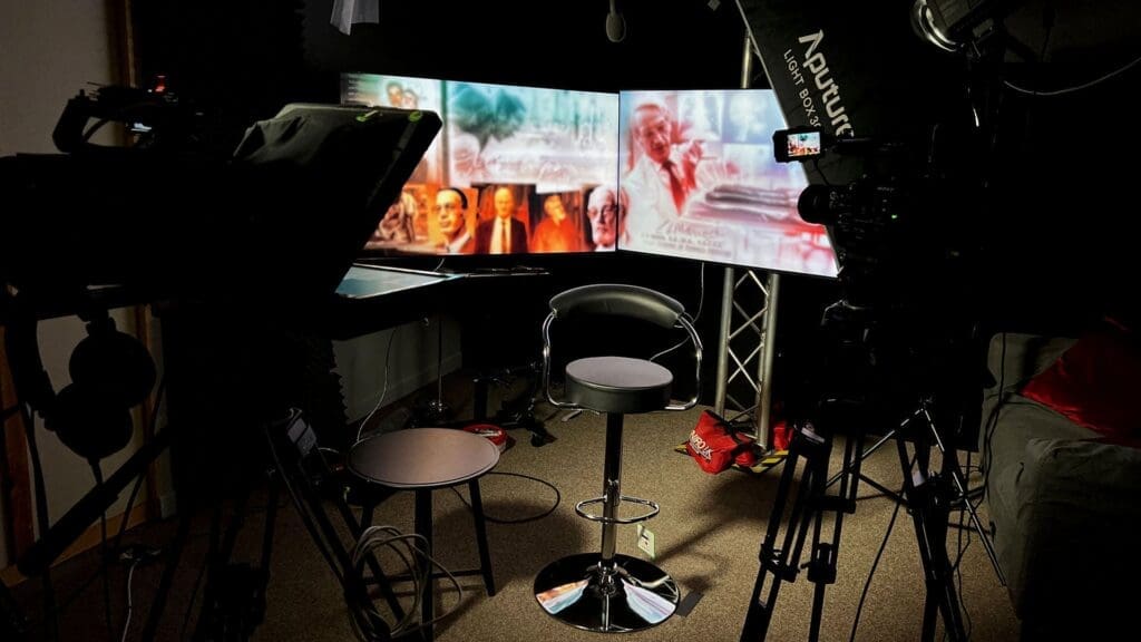 Video production studio with multiple screens setup in blacked out space.