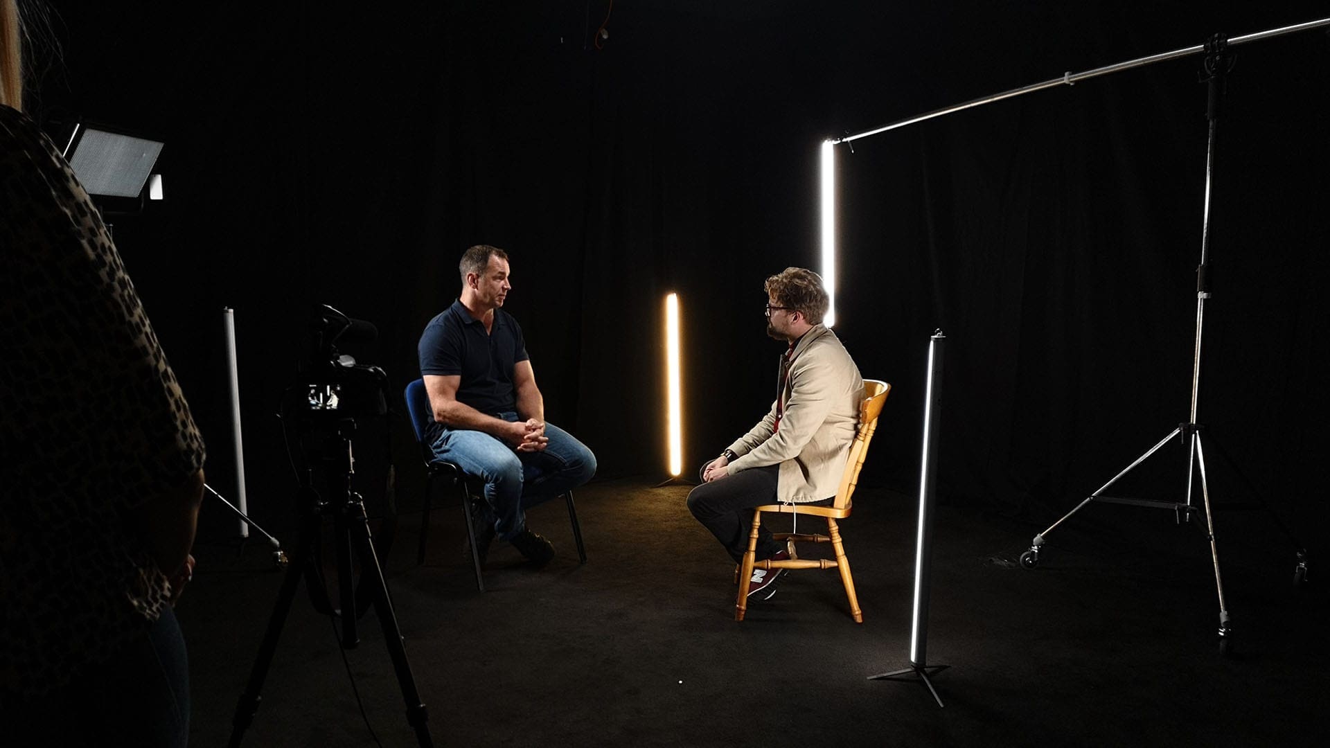 Two people having a conversation in blackout studio.